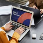 Two professionals work on laptops focusing on digital advertising in an office setting.
